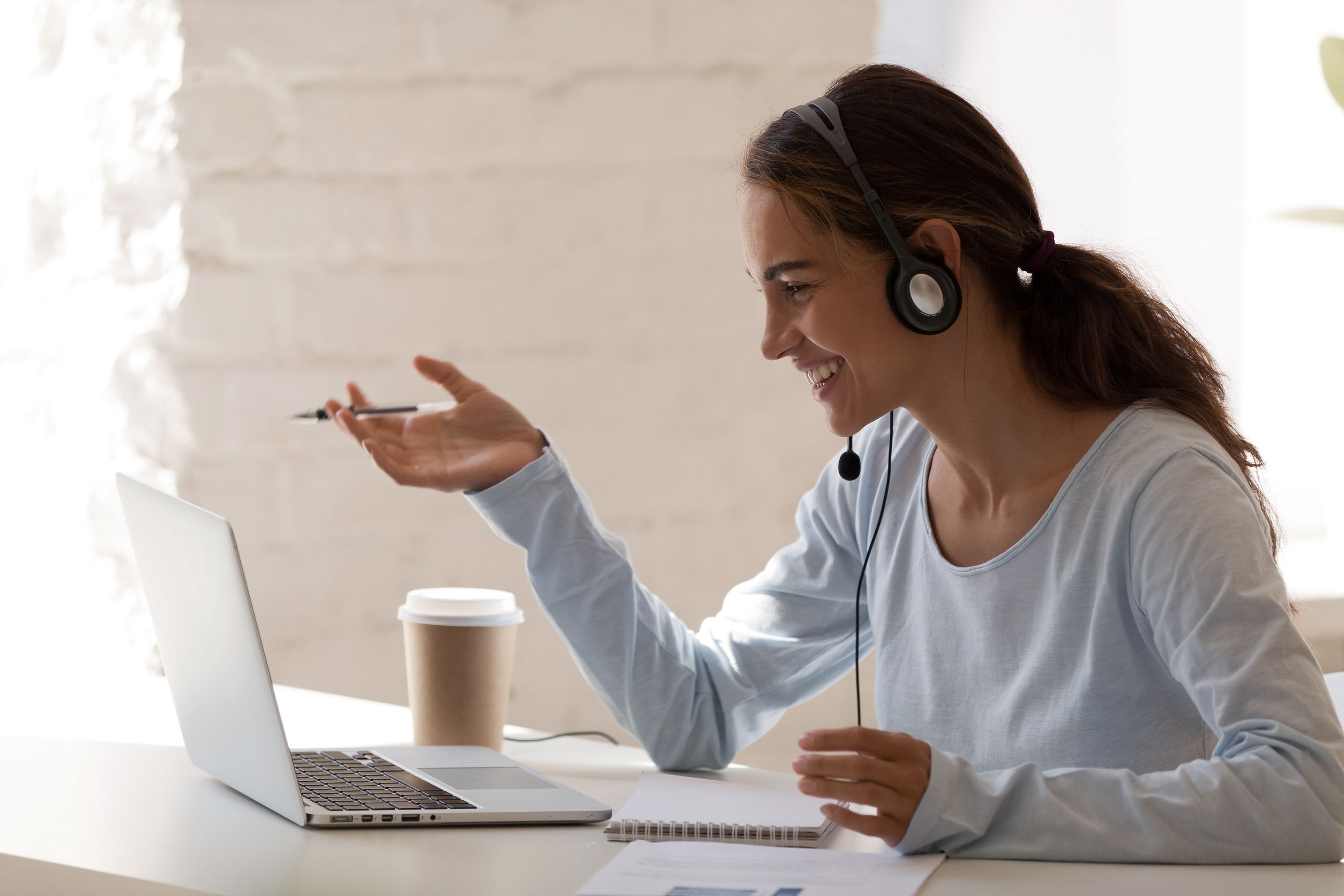 Smiling millennial lady freelancer wearing headset, communicating with client.