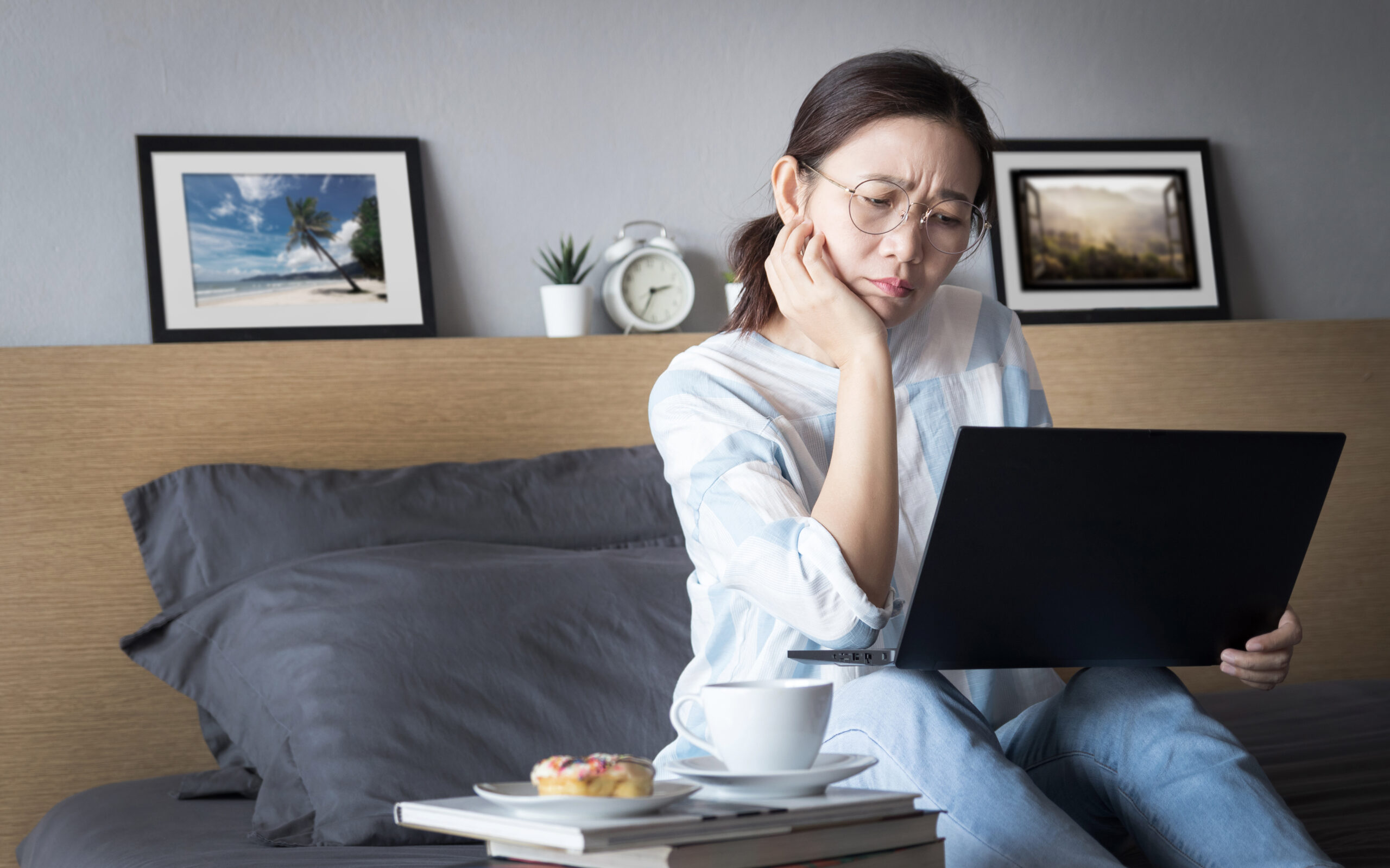 working from home, new normal concept. woman working with laptop computer on bed from her room during self isolation with stress emotion during transmission of COVID-19 Coronavirus pandemic