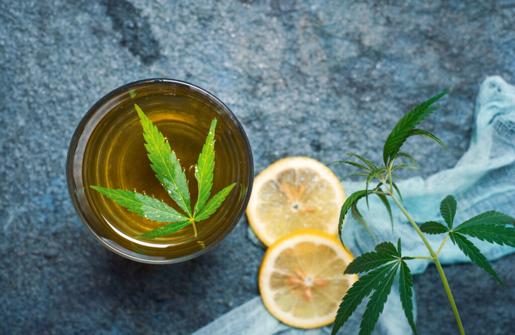 Marijuana tea with cannabis leaves in a glass on stone table top view