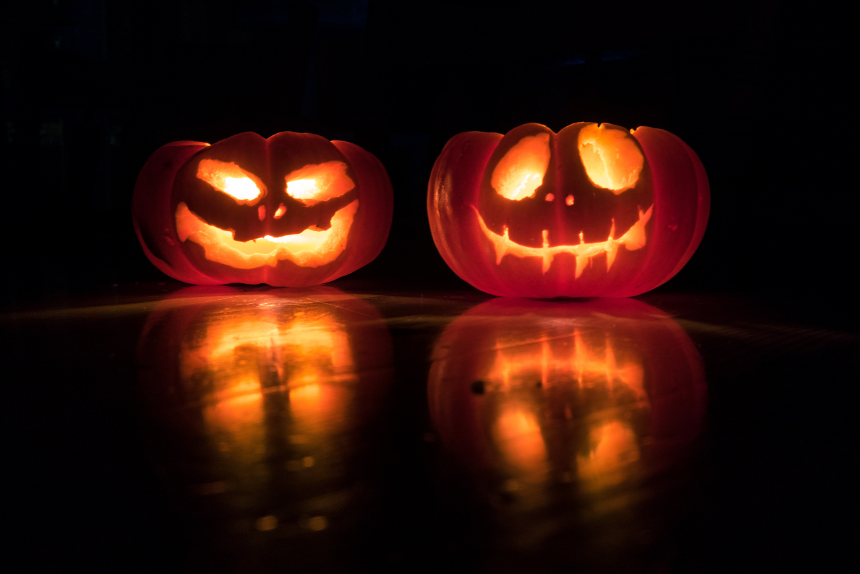 Two jack o lanterns aglow in the dark on a story about comms horror stories
