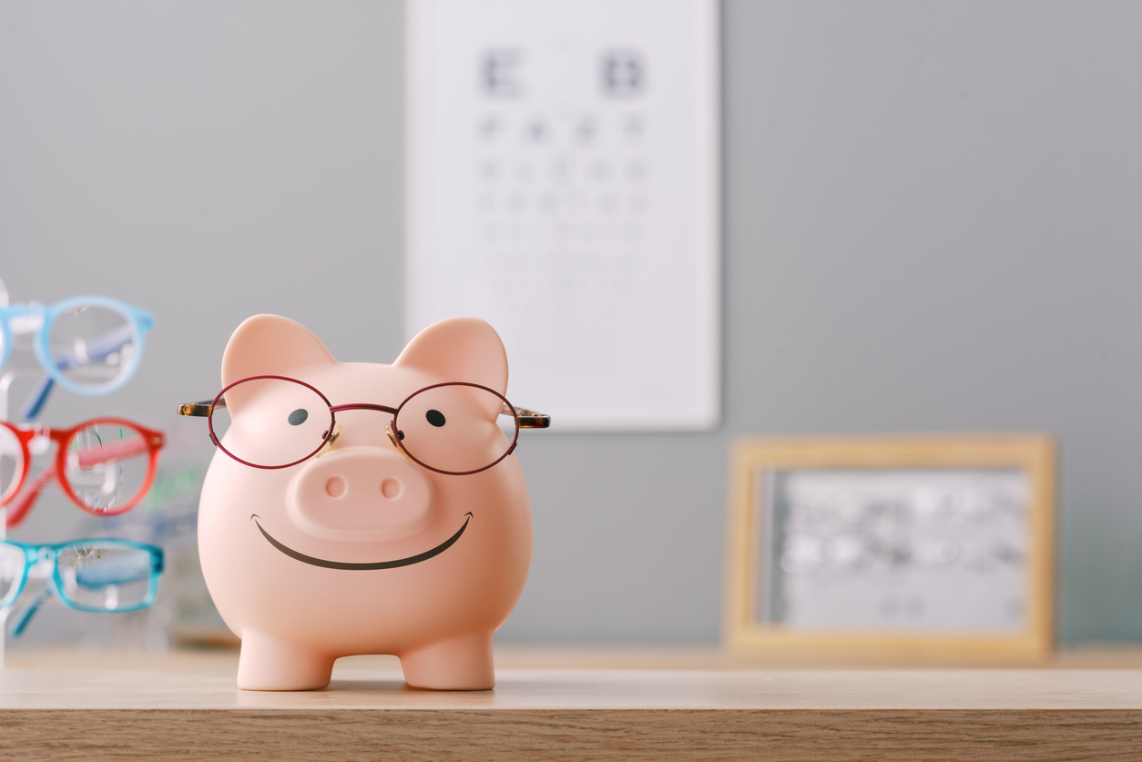 Happy piggy bank at the optician shop wearing new glasses, copy space